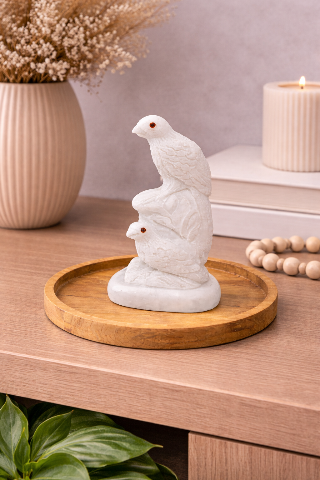 Hand-carved white marble bird sculpture with red gemstone eyes on wooden tray