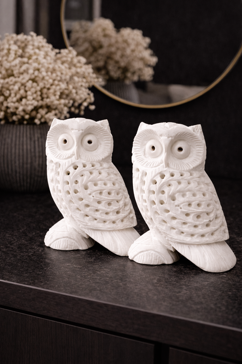 Set of two hand-carved white marble owl sculptures on black console table – luxury home décor