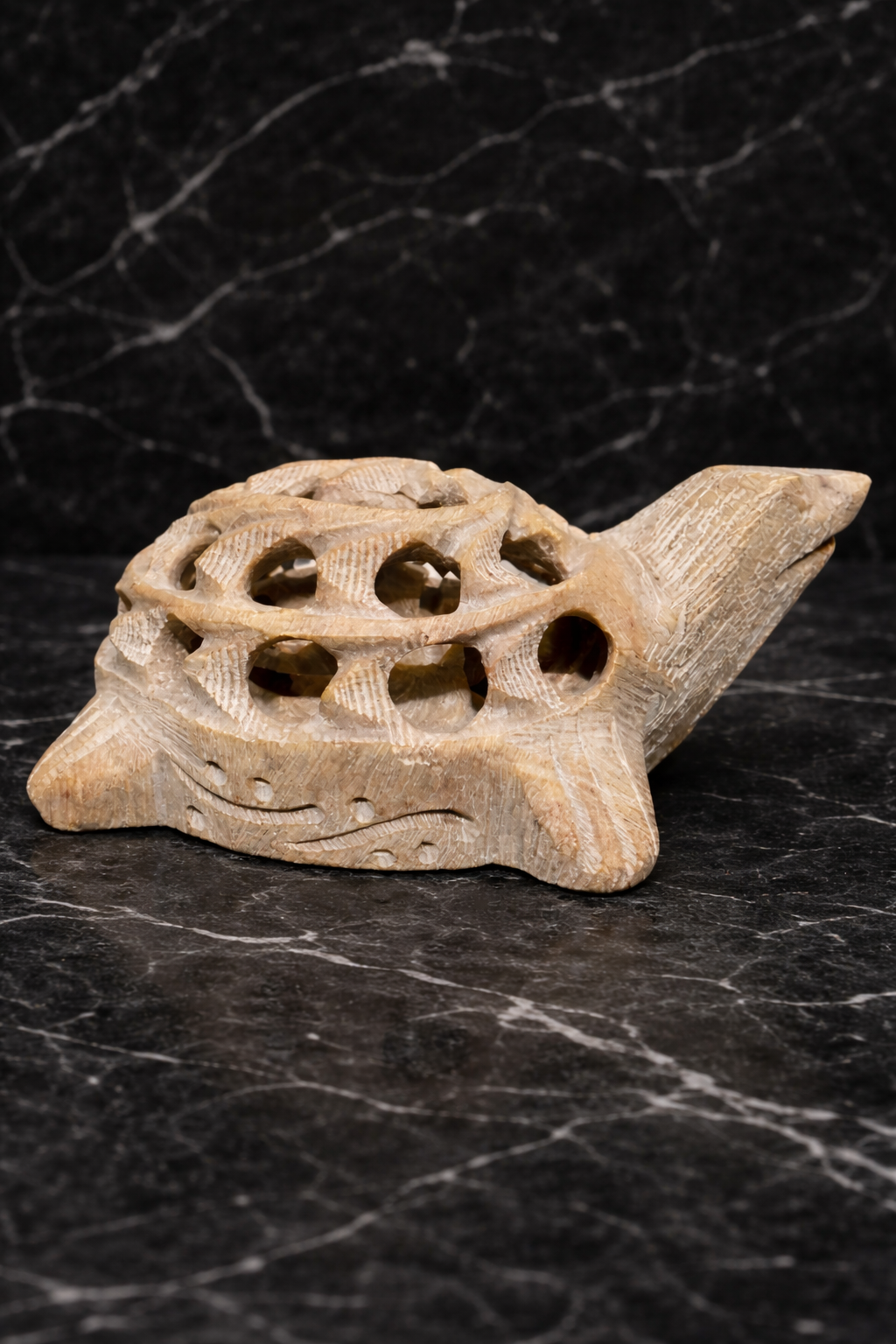 Hand-carved white marble turtle sculpture with intricate lattice shell design on marble surface