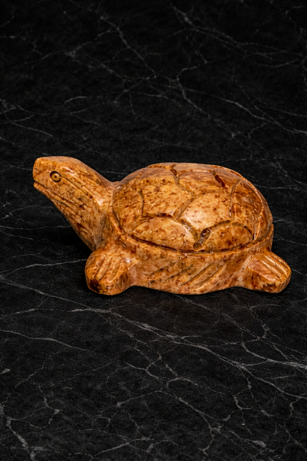 Natural brown soapstone turtle figurine with polished finish on dark marble background