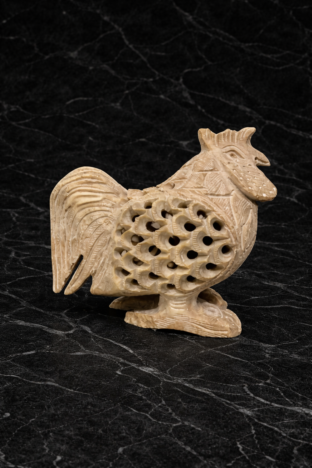 Hand-carved soapstone rooster sculpture with jali openwork on black marble surface