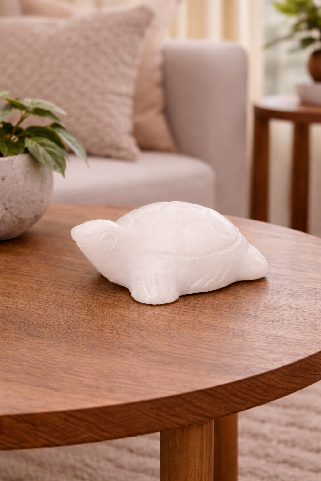 Small white marble turtle sculpture displayed on round wooden table