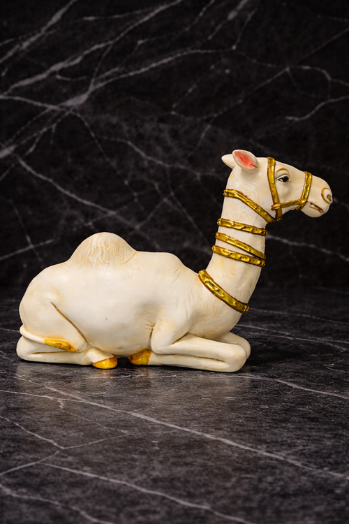 White camel figurine with gold detailing on a dark marble background