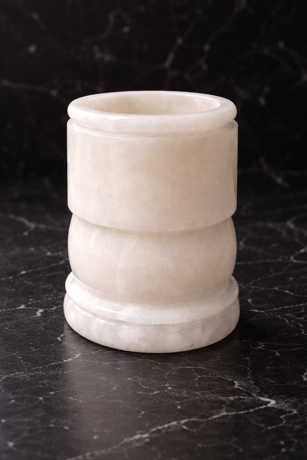 Onyx cylindrical vase on a dark marble surface