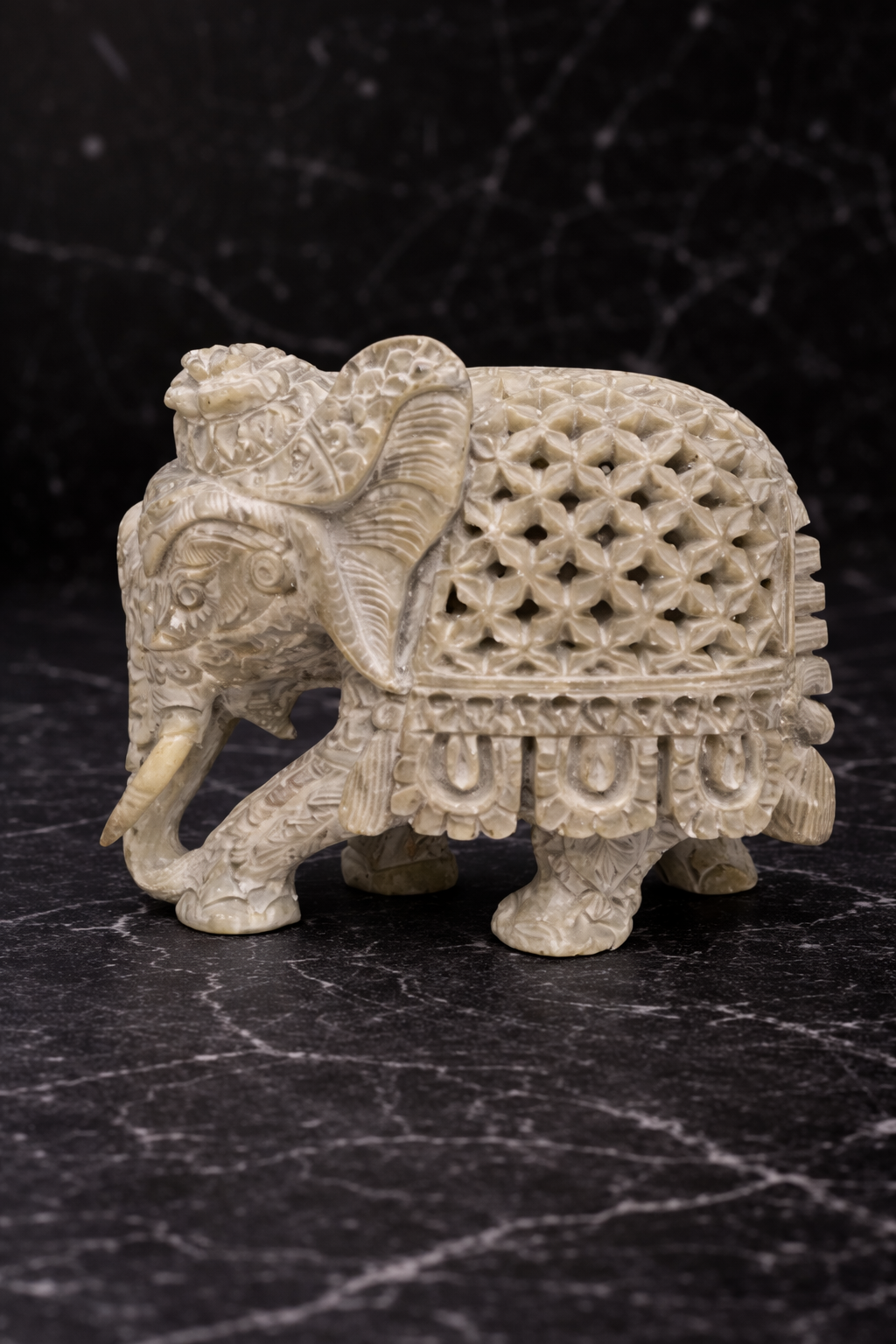 Hand carved soapstone elephant sculpture with hidden inner elephant design on black marble background