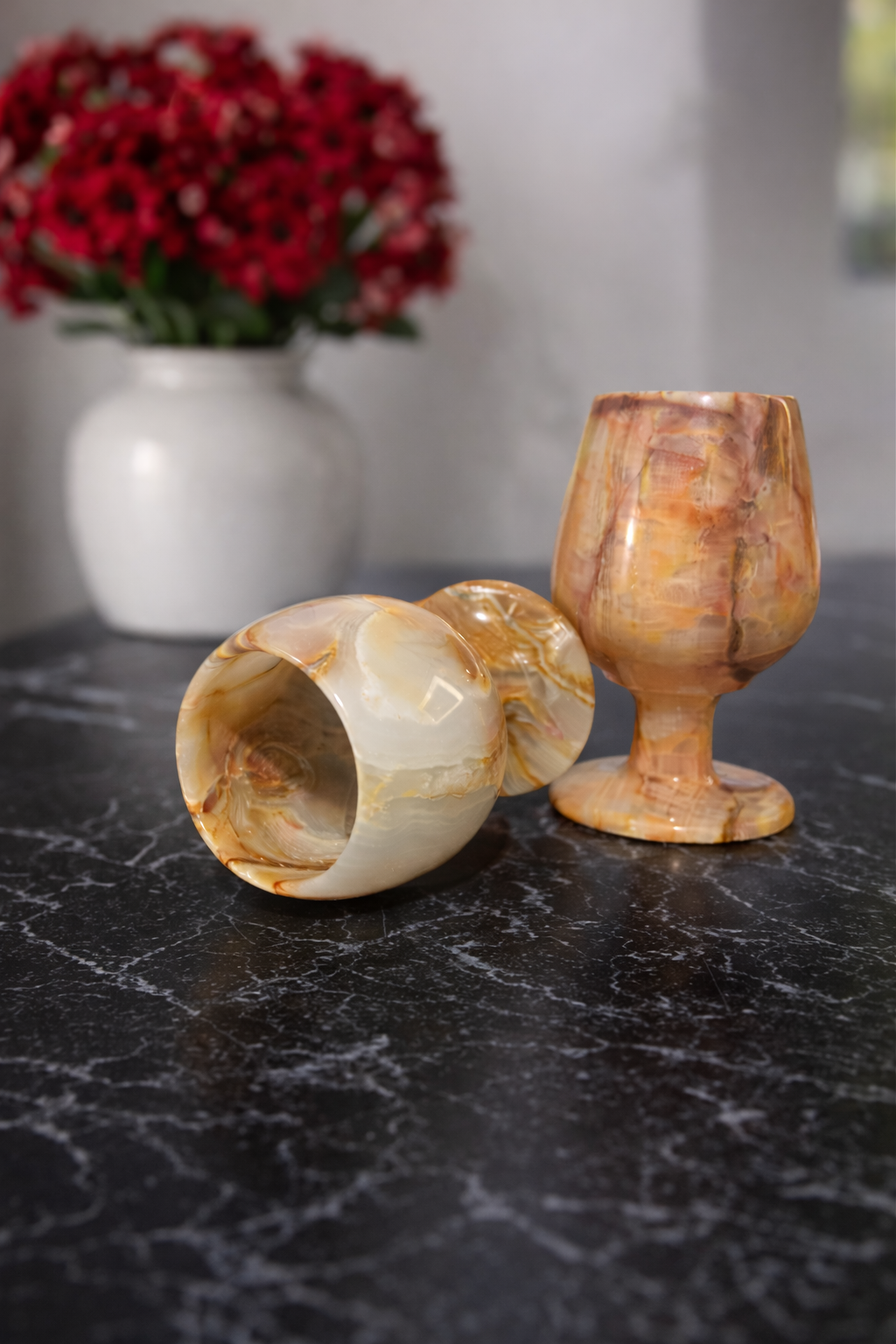 Natural onyx wine goblets with cream and amber veining on marble surface