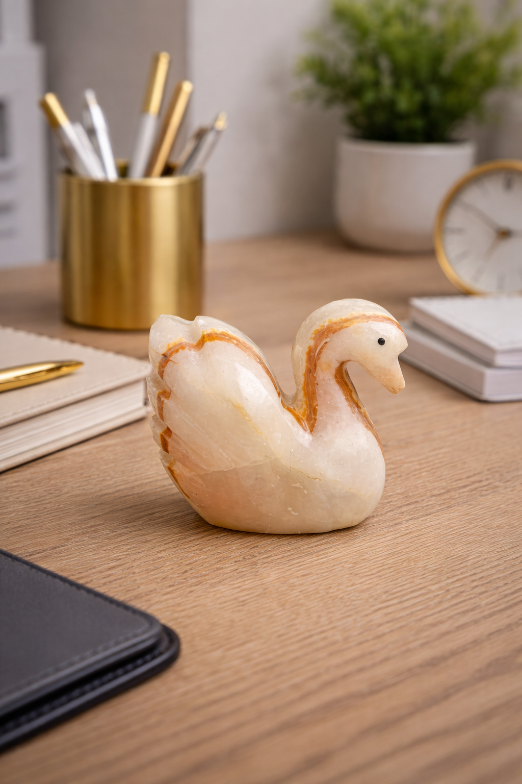 Handcrafted natural onyx swan figurine placed on modern office desk