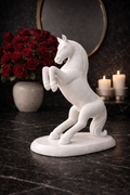 Hand-carved white marble rearing horse sculpture on marble base with candles and red roses