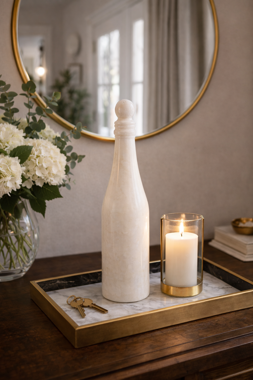 Hand-carved marble wine bottle styled with mirror and floral vase for luxury interior decor