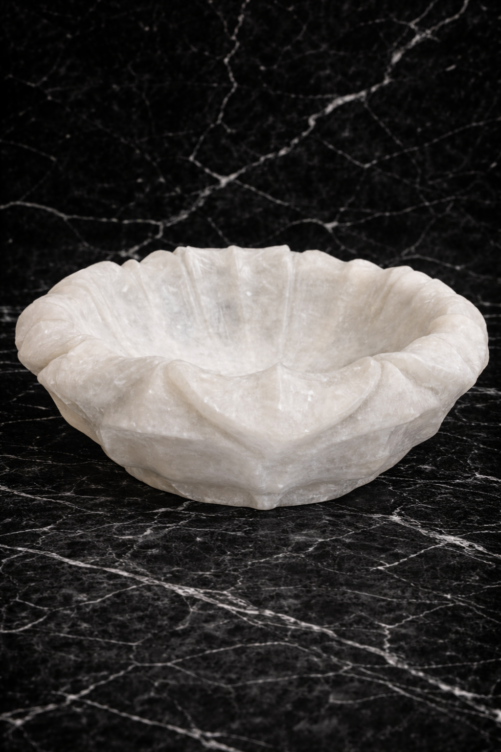 Hand-carved white marble lotus decorative bowl with sculpted petals placed on a black marble surface
