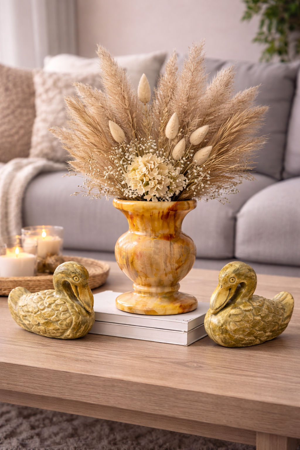 Pair of hand-carved soapstone duck figurines on wooden coffee table with stone vase and dried flowers in home