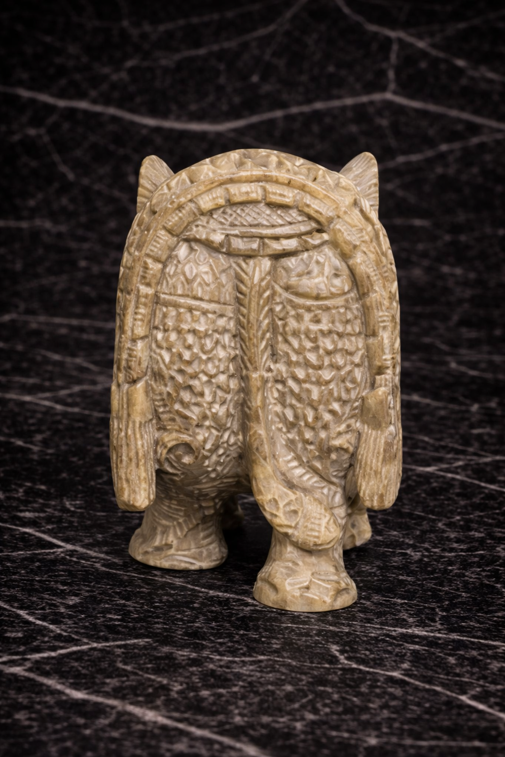 Rear view of hand carved soapstone elephant sculpture with intricate floral detailing and hidden inner elephant design on black marble background NZ