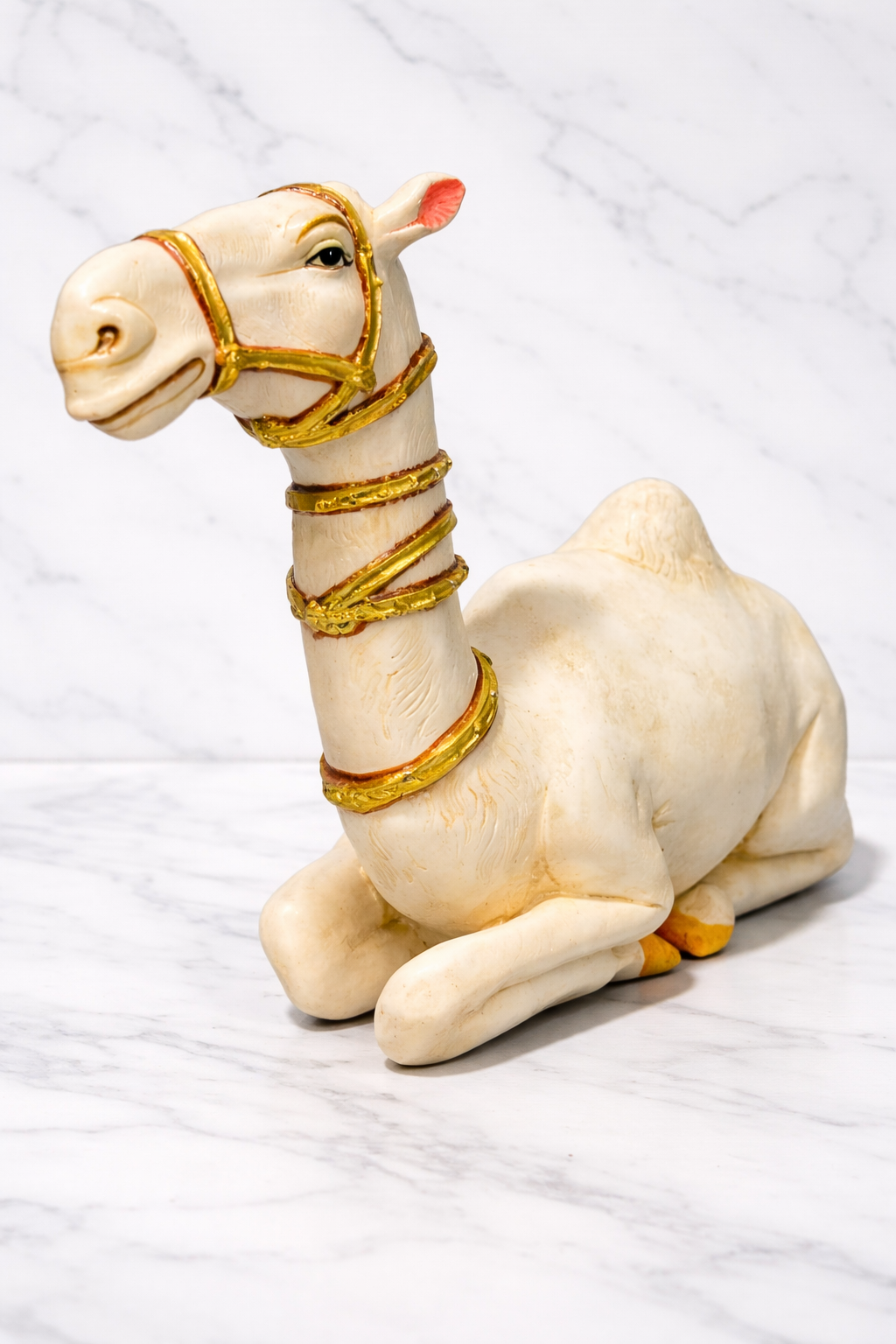Luxury camel figurine in white with gold details on a white marble tabletop