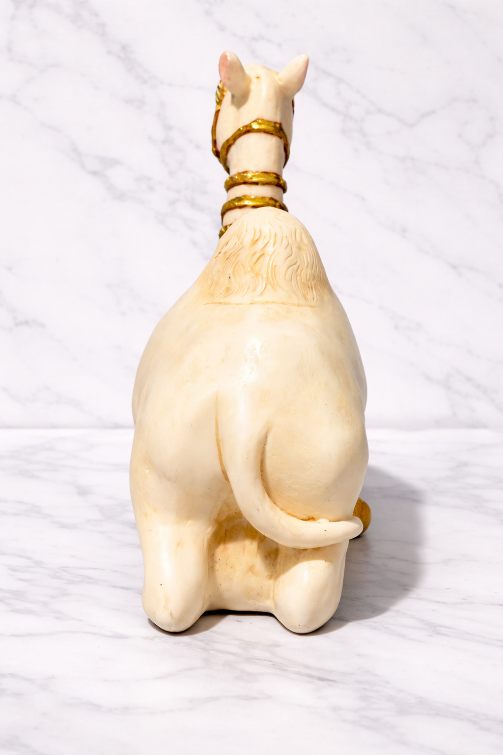 Back view of a camel figurine on white marble