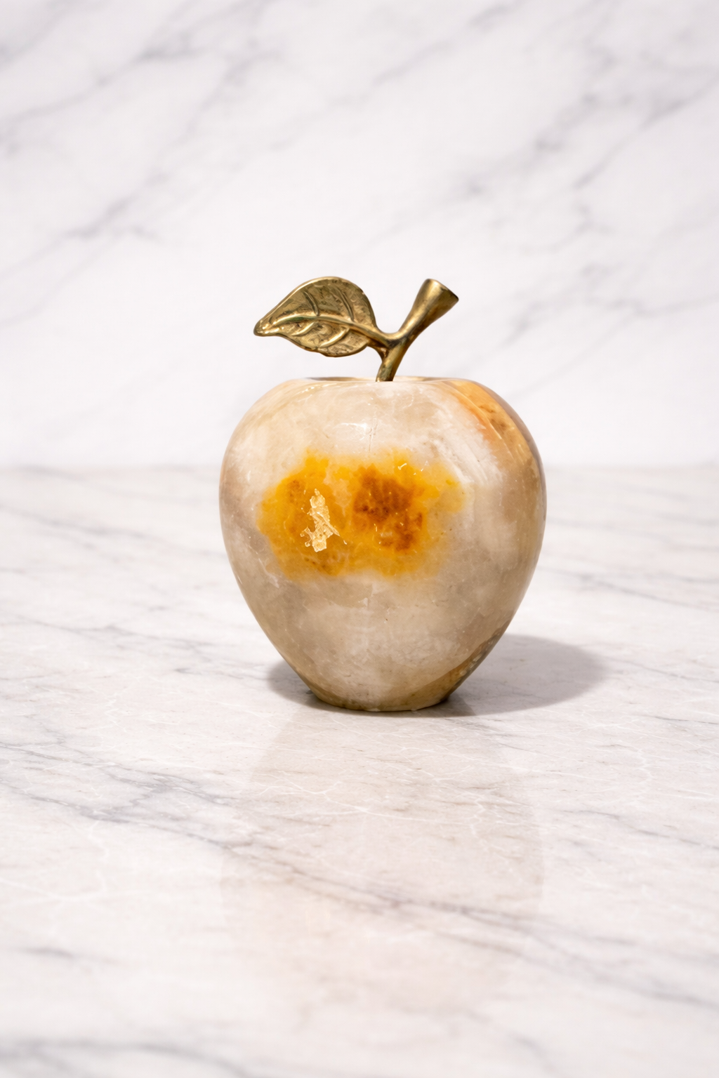 Side view for Onyx apple decor with metal leaf stem on a white marble surface