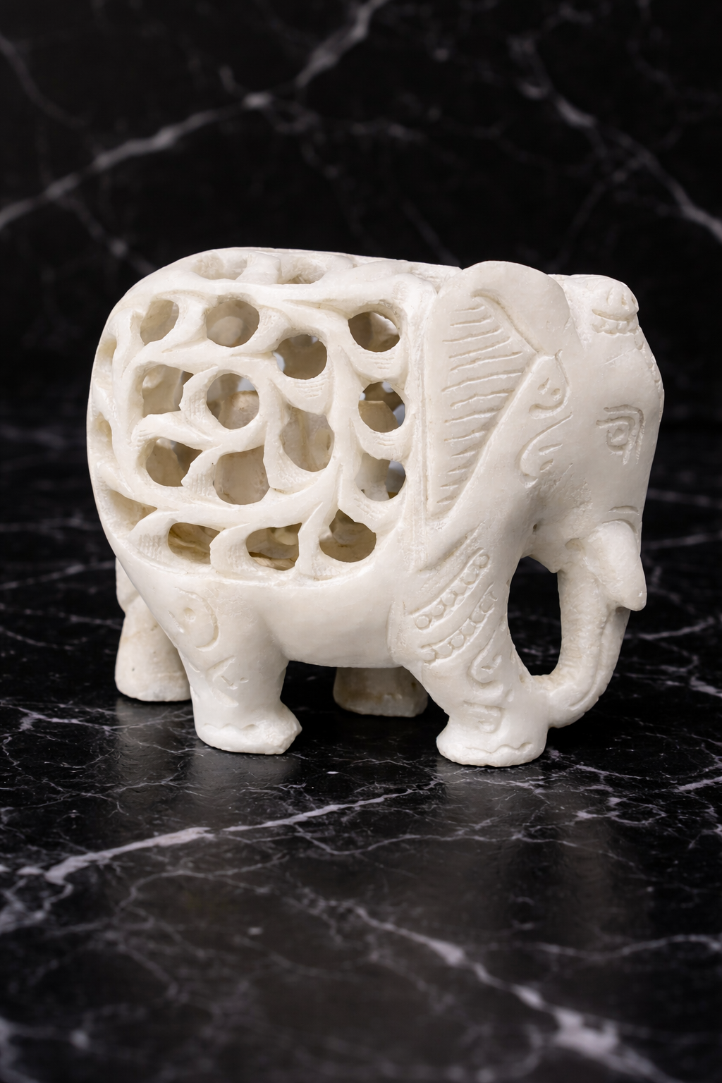 Hand-carved marble elephant with baby sculpture on dark marble surface
