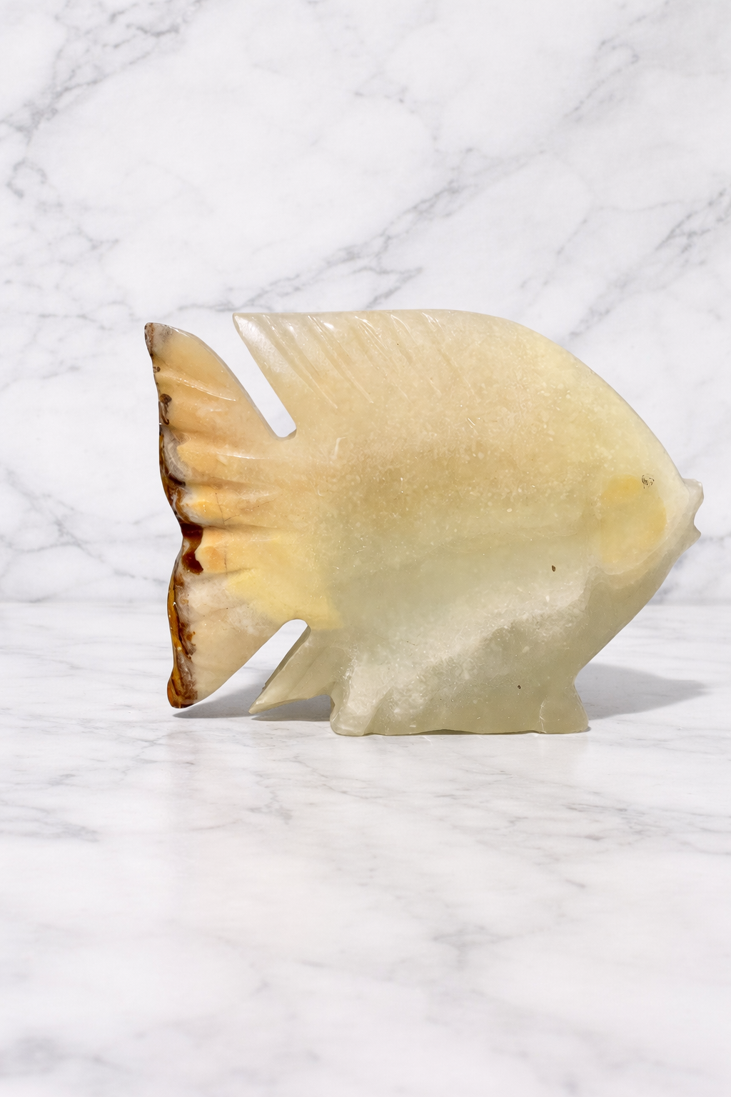 Hand-carved onyx fish sculpture 0.336 kg on marble surface