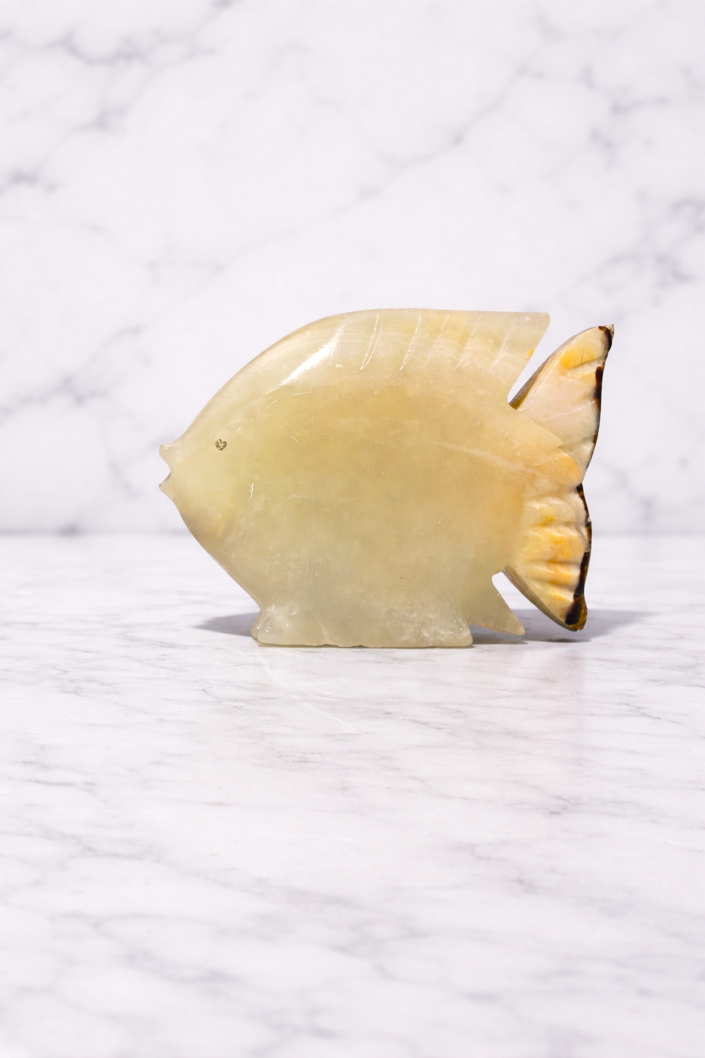 Hand-carved onyx fish sculpture on marble background