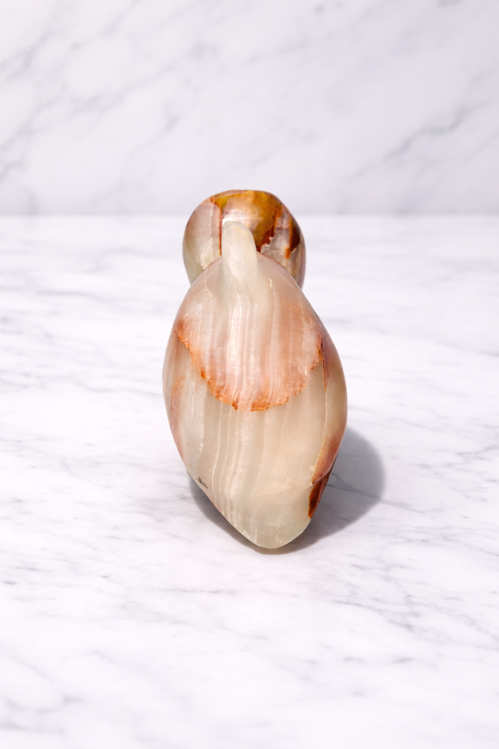 Hand-carved onyx dolphin sculpture on white marble surface