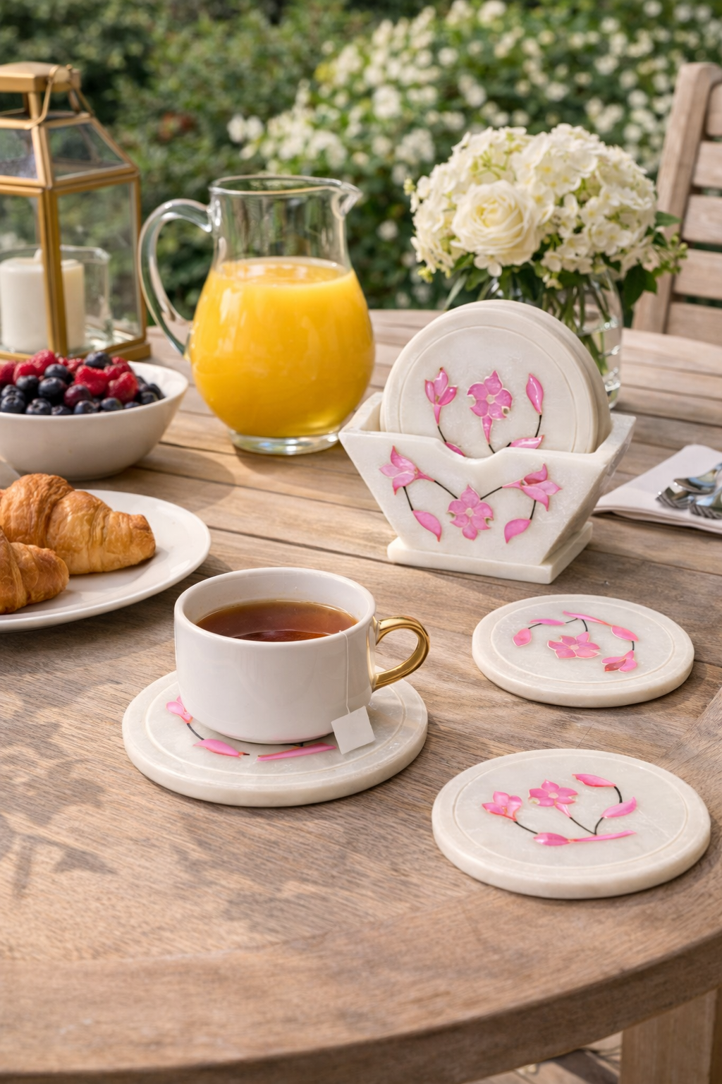 Marble drink coaster set with floral inlay on outdoor lounge table with glass of juice – luxury patio drink coasters