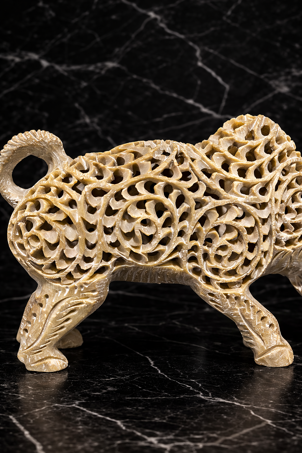 Close-up of hand carved soapstone bull showing intricate floral lattice stone carving and artisan craftsmanship