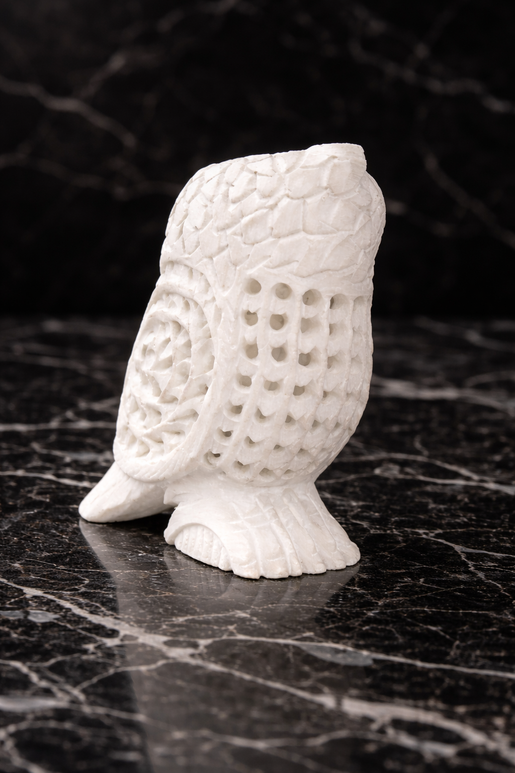 Rare view of hand-carved white marble owl sculpture on black marble surface – luxury stone home décor