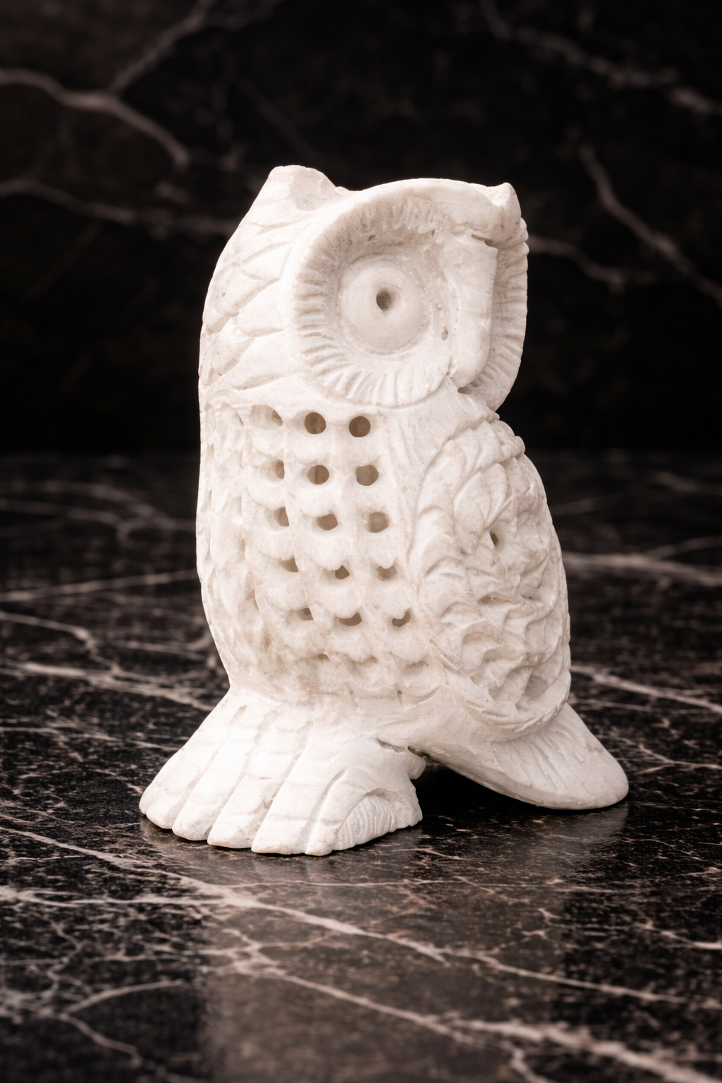 Hand-carved white marble owl sculpture on black marble surface – luxury stone home décor