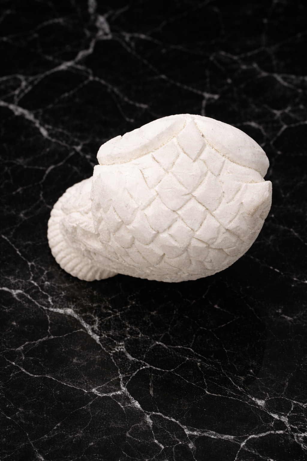 Top view of hand-carved white marble owl sculpture on black marble surface – luxury stone home décor