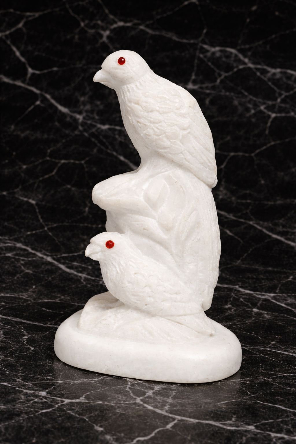 Hand-carved white marble bird sculpture (side view) with red gemstone eyes on black marble surface