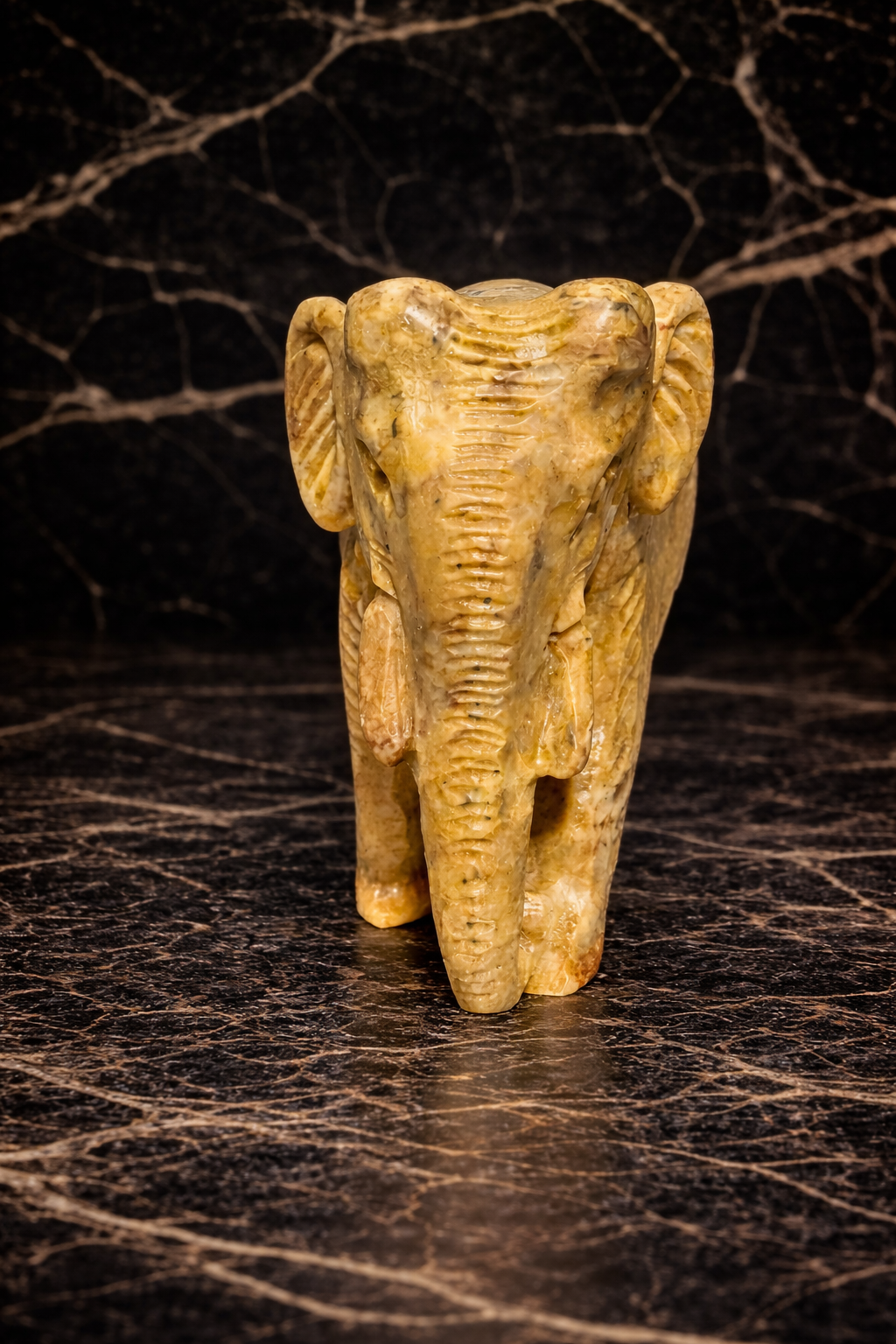 Front view of Hand-carved stone elephant figurine on dark surface