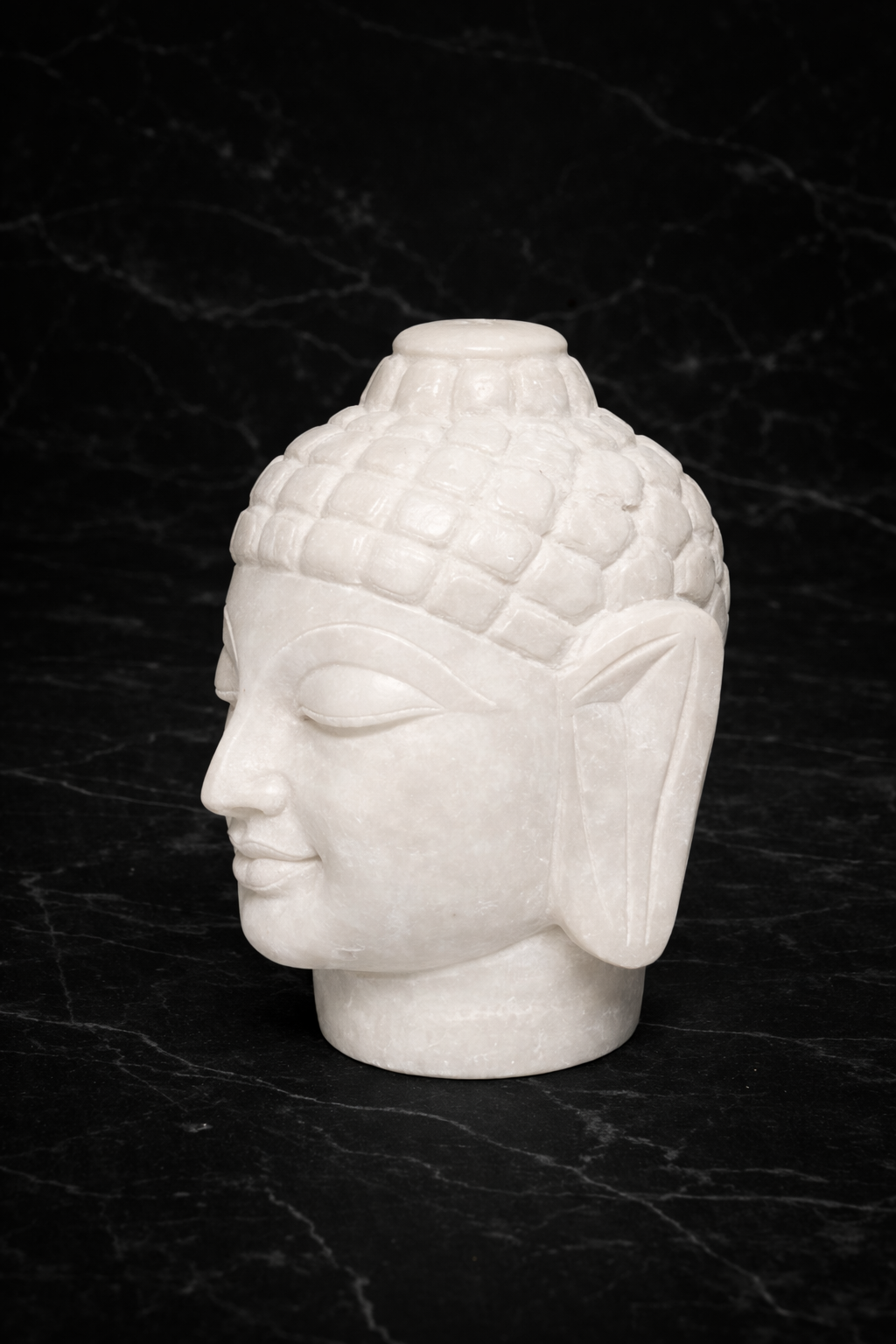side view of Hand carved white marble Buddha head statue on black marble background