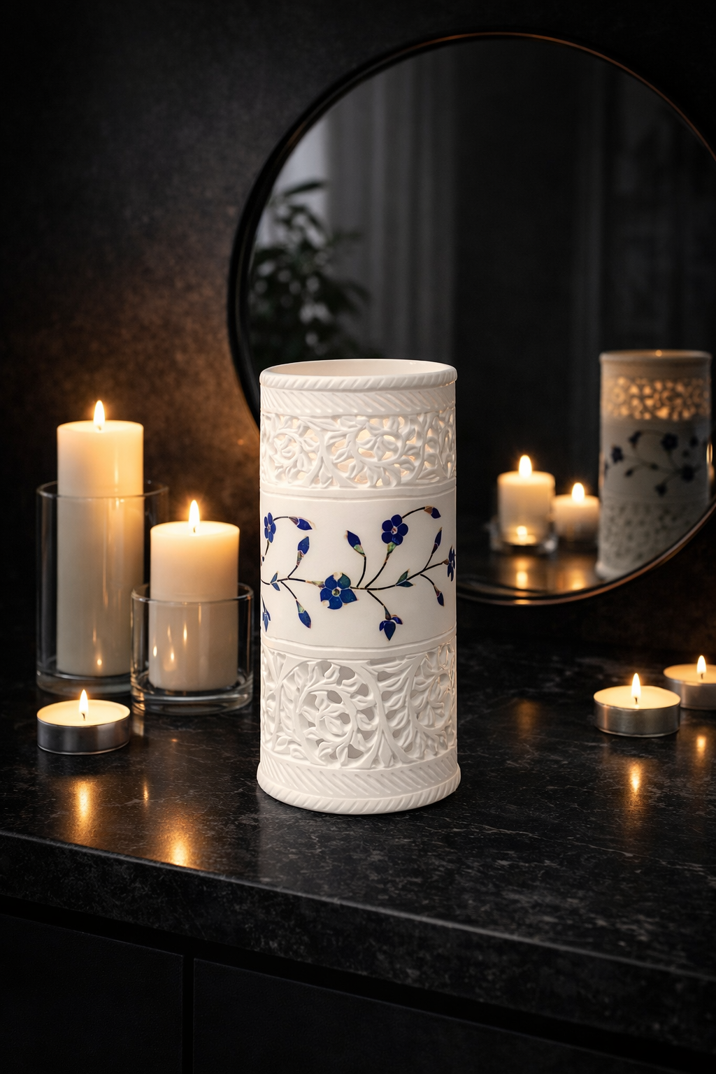 Hand-carved white marble tealight holder with blue floral inlay on a black marble table surrounded by lit candles, luxury home décor accent.