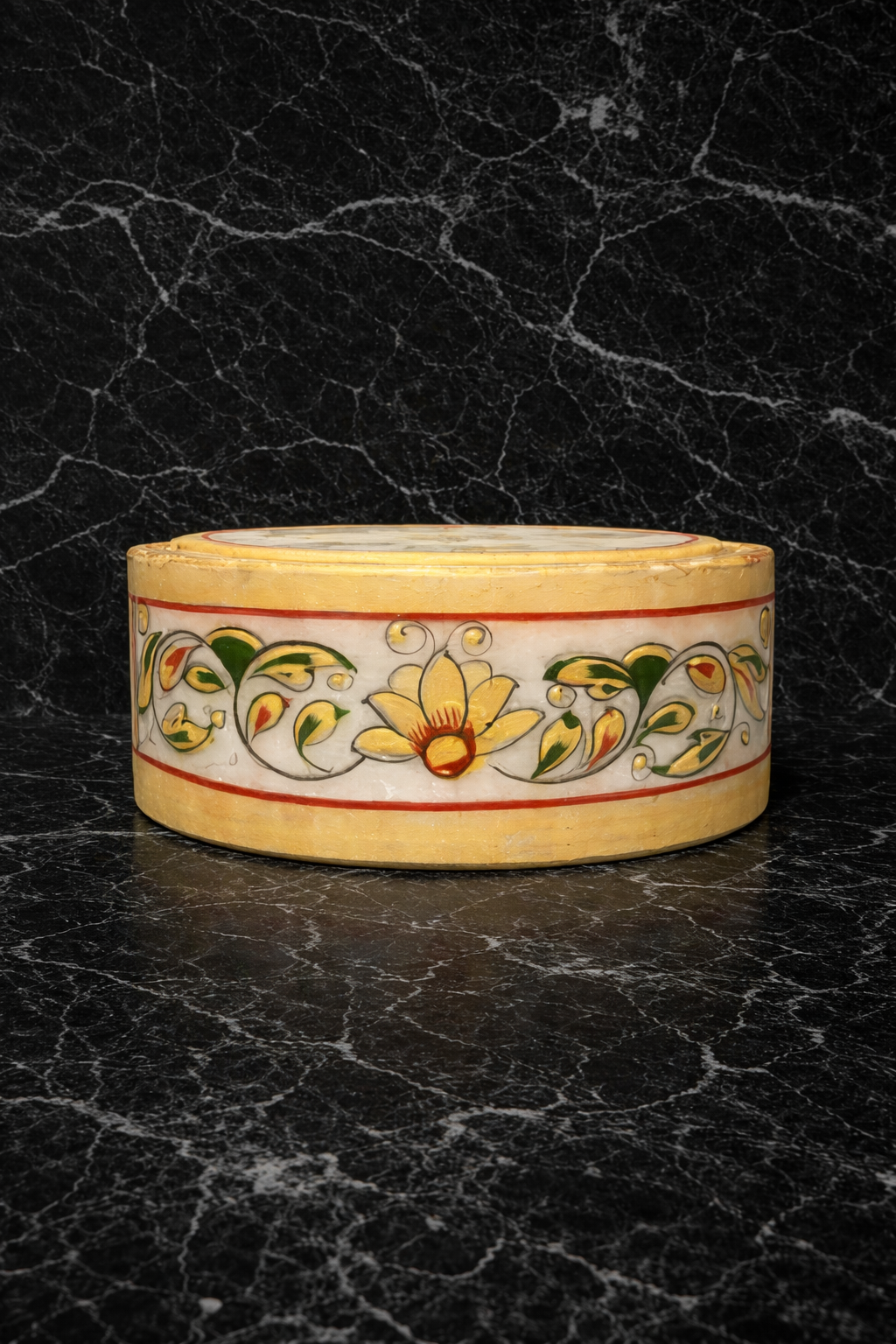 Handcrafted marble drink coaster with floral hand painting and gold holder on dark marble background.
