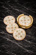 Handcrafted white marble coaster set with hand painting design and gold holder displayed on a black marble surface.