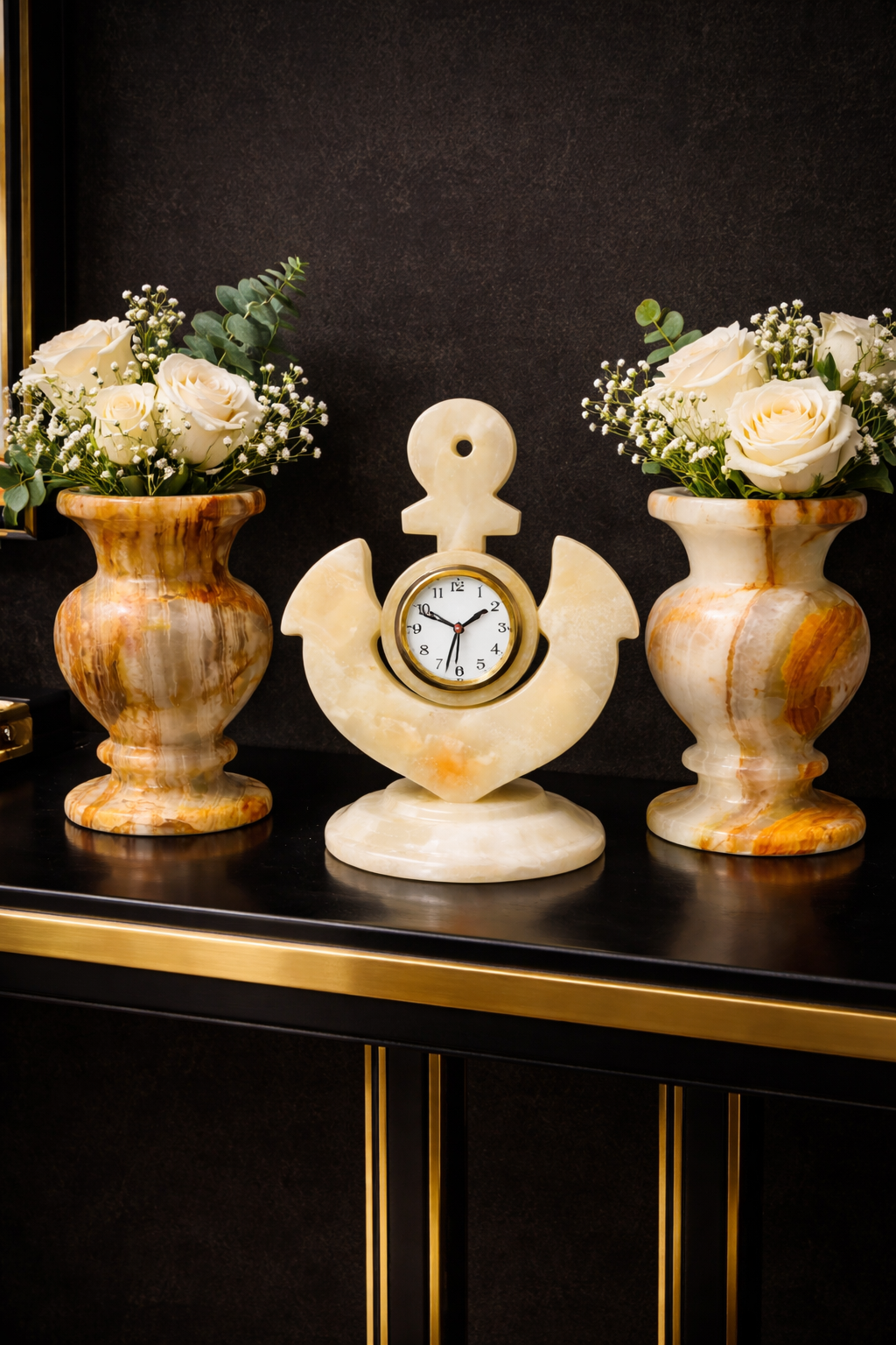 White marble anchor desk clock displayed between natural onyx vases on a luxury entry console table with dark background décor.