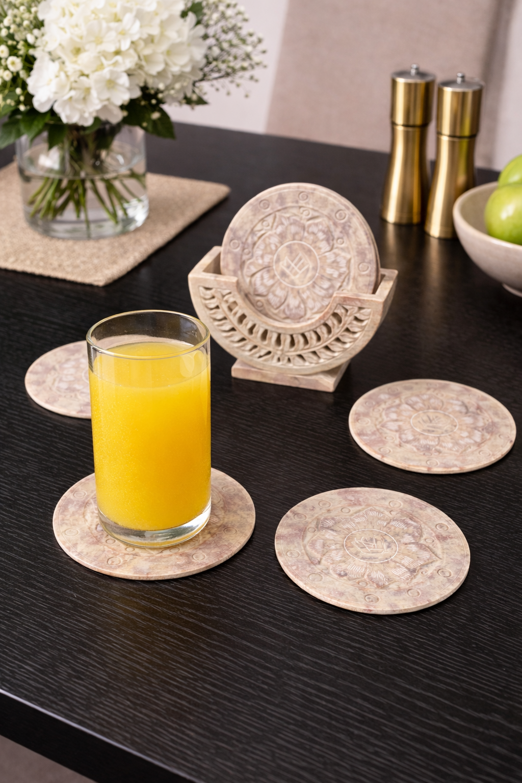 Soapstone lotus coaster set with holder and glass of juice on black dining table