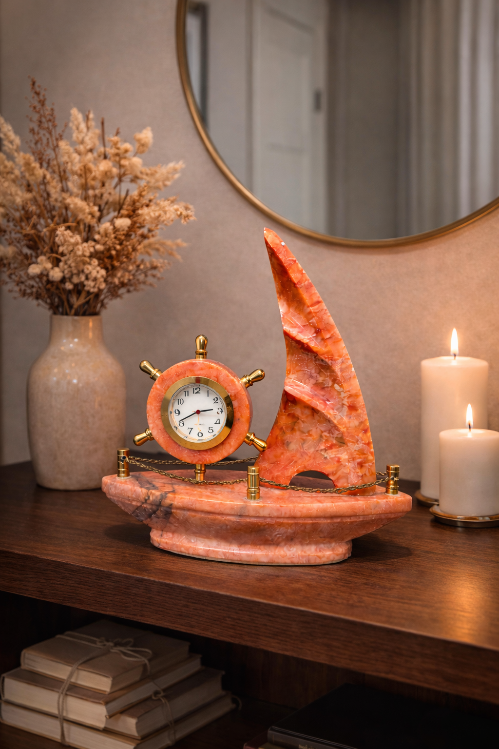 Red onyx sailboat marble clock on entryway console table with candles and dried flower vase – elegant nautical home décor.