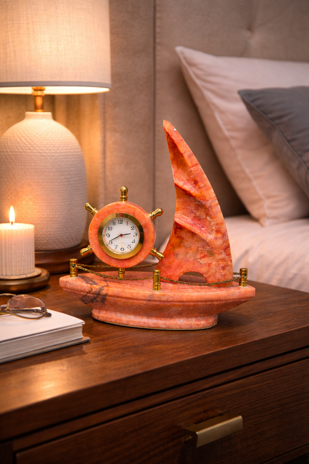 Luxury red onyx sailboat marble clock placed on bedside table – nautical stone décor for bedroom styling.