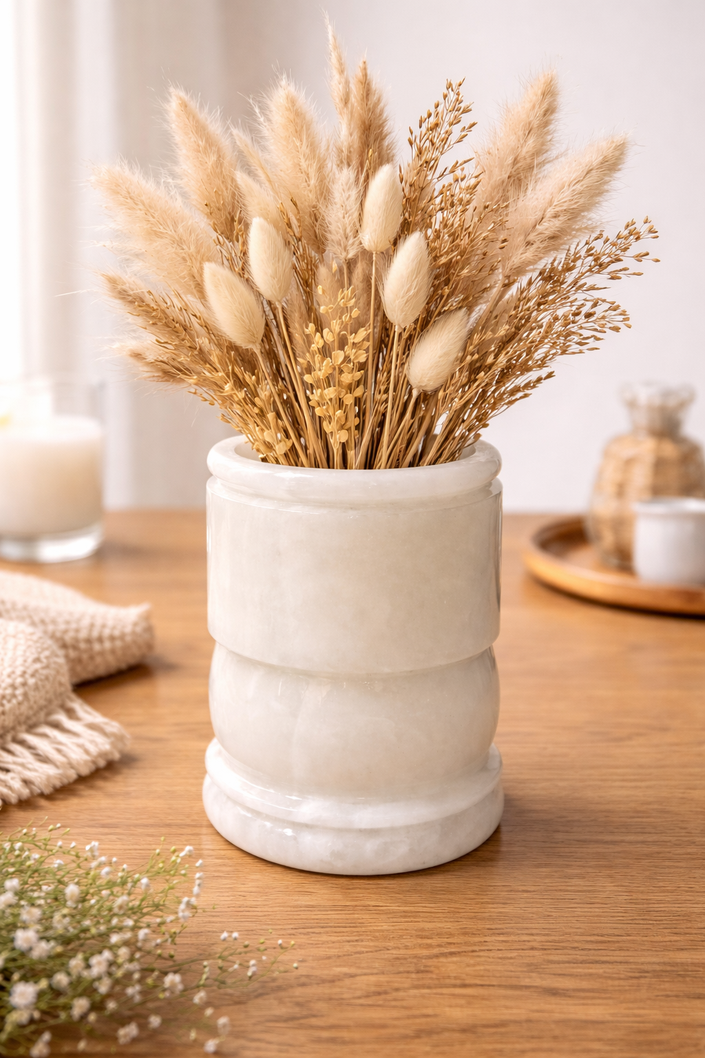 Natural onyx stone vase with dried pampas and wheat stems on a wooden table, minimalist neutral home décor.