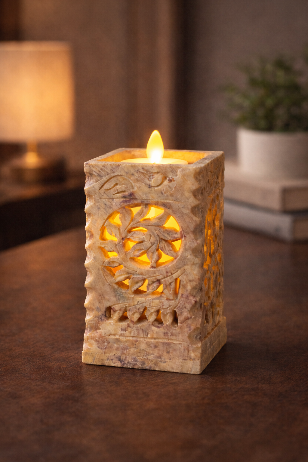 Hand-carved soapstone stand with floral cut-out pattern holding a glowing tealight candle.